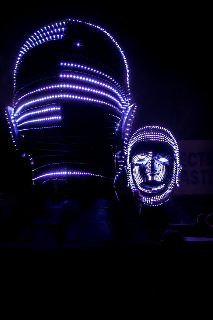 services-02 Abstract LED light sculptures resembling human faces illuminating a dark setting, showcasing modern artistry.