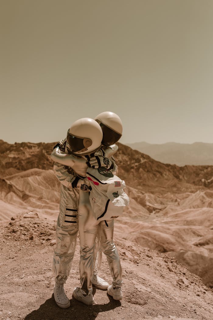 services-03 Two astronauts in space suits embrace in an arid, Mars-like desert setting, conveying a sense of sci-fi and exploration.